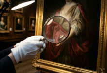 Personne gantée examine un tableau classique à la loupe sous une lampe. Scrutin d'authenticité dans une galerie.