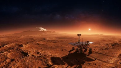 Un rover robotique sur la surface rouge de Mars au crépuscule, avec un soleil lumineux, une montagne enneigée et un ciel étoilé.